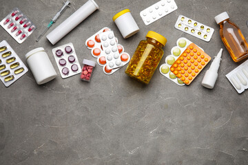 Different pills, syringe and bottles of medicines on grey background