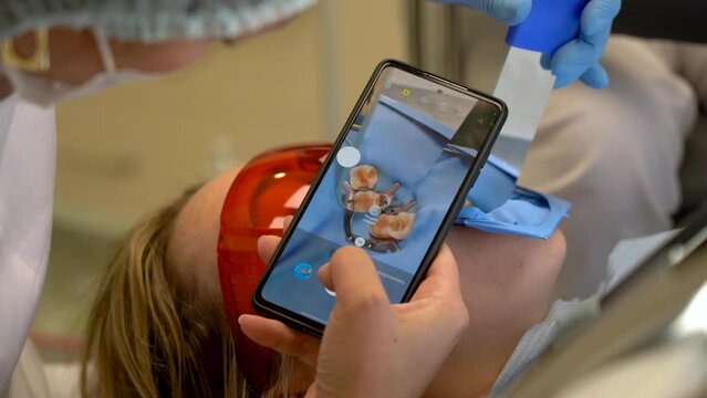 A dentist takes a photo of a diseased tooth on a smartphone before treatment.