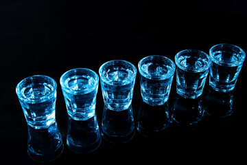 Shots of cold vodka on black background