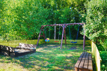 lawn with playground in the garden. sandbox, swings and benches. - obrazy, fototapety, plakaty