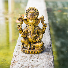 Gold Ganesha statue on a trunk over the water.