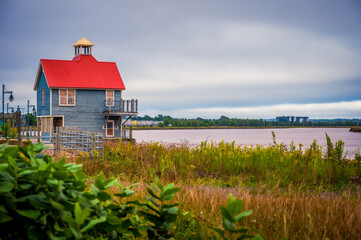 Petitcodiac River and small building with red roof with dramatic sky, Bore Park, Moncton, New...