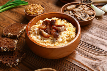 Bowl of tasty banosh on wooden background