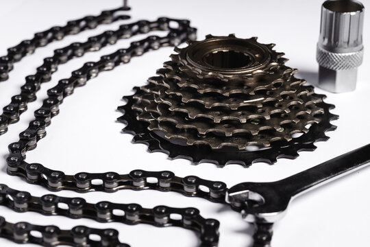 bicycle sprocket and chain lying on white background, next to bicycle repair tools (selective focus)