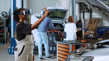 Licensed engineer in auto repair shop using virtual reality goggles to visualize car components in...