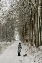Woman with a dog on a walk in the winter forest