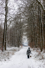 Woman with a dog on a walk in the winter forest