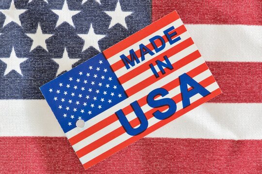 Made in USA label sitting on top of a partial American flag, an economy concept. Macro image with patriotic background details.