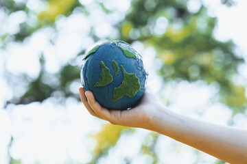 Young boy's hand holding planet Earth globe at natural park background as Earth day to save this...