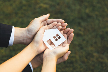 Businessman hold house icon together with child's hand, presenting house loan opportunity as part...