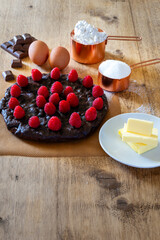 Chocolate and raspberries cake with ingredients on a wooden table