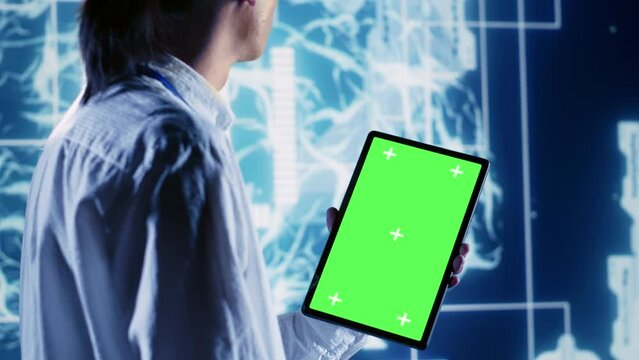 Skillful IT consultant using green screen tablet to implement artificial intelligence parallel processing. Dilligent supervisor oversees chroma key device enabling AI to do machine learning inference