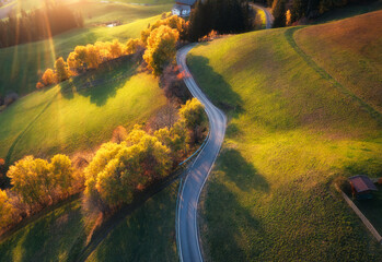 Aerial view of road in alpine meadows and hills at sunset in autumn. Top view of rural mountain...