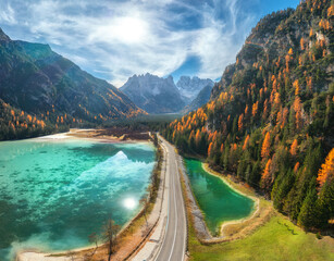 Aerial view of road, azure lakes, forest in alpine mountains in autumn sunny day. Dolomites, Italy....