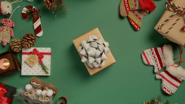 Merry Christmas concept RED camera shot 4K. Top down view of elegant craft paper gift box with shiny silver bow on green backdrop. Holiday ad background perfect for website and social media campaigns