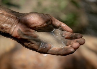 Fototapeta premium Detail of man holding wet clay at a natural spring spa