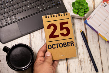 October calendar background with number 25. Stationery pens and pencils in a case on a wooden...