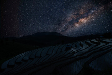 Milky way in the dark night over Pa Bong Piang rice terrace fields and light from countryside...