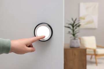 Man adjusting thermostat on white wall indoors, closeup. Smart home system