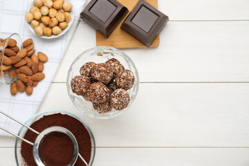Tasty chocolate balls and ingredients on white wooden table, flat lay. Space for text