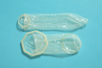 Unrolled female and male condoms on light blue background, flat lay. Safe sex