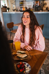 Happy young woman having fun with her friends sitting at a brunch cafe restaurant