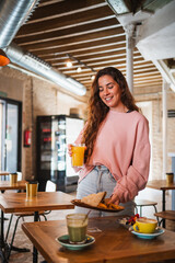 Cute young woman putting her food on the table. She is having brunch at a cafeteria.
