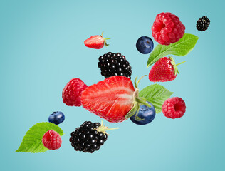 Many different fresh berries falling on light blue background