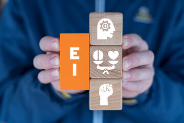 Hands holding colorful blcoks with icons and abbreviation: EI. Emotional and intelligence quotient....