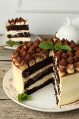 Delicious tiramisu cake with mint leaves on wooden table