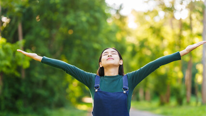Happy young Asian woman relaxing outdoors, Enjoy beauty of nature and find inner peace on a sunny afternoon, relax time, love your self.