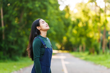 Happy young Asian woman relaxing outdoors, Enjoy beauty of nature and find inner peace on a sunny afternoon, relax time, love your self.