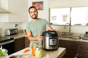 Happy young man cooking lunch food with a pressure cooker in the kitchen