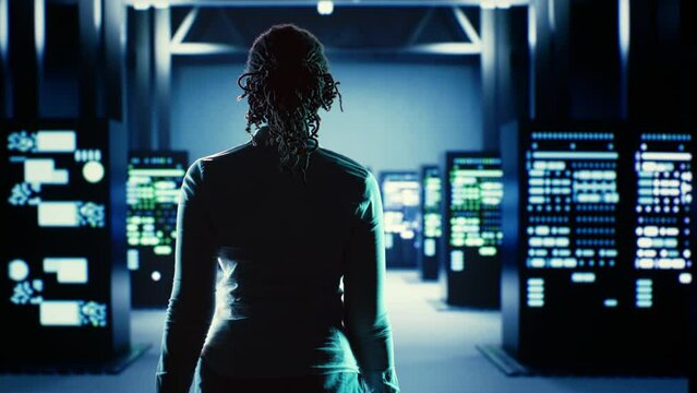 Skillful employee strolling around data center server rows, looking for damages in high tech workspace equipment designed to accommodate server units, networking systems and storage arrays