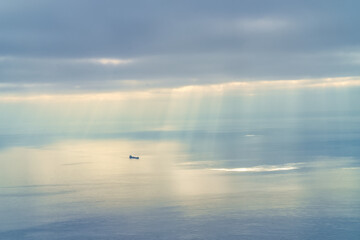 Fototapeta premium Shafts of sunlight break through the clouds over a great lakes freighter, Lake Superior, Michigan.