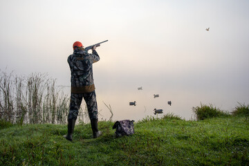 Hunter shooting to the flying duck. Hunting season concept.