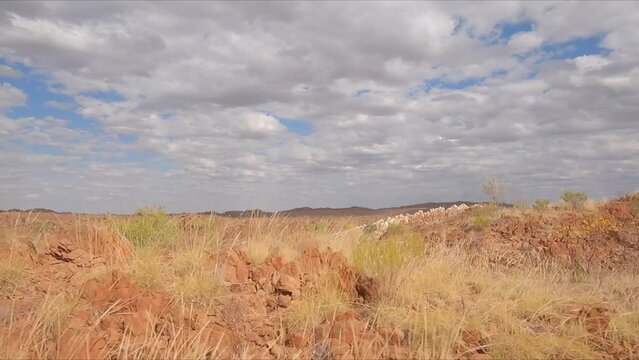 Driving past red geological rock outcrops heading north along Western Australian highway from Perth