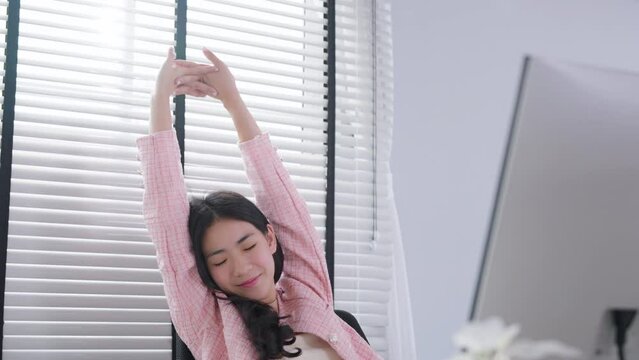 Office syndrome concept. Young asian woman feeling pain in neck and shoulder after working on computer laptop for a long time. She stretches to relax her muscles