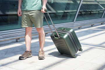 Young man with green suitcase near the airport, travel concept.