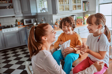 Obraz premium Young mother and her kids having breakfast together and being messy in the kitchen