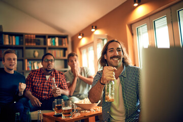 Young and diverse group of friends watching sports on the tv in the living room