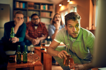 Young and diverse group of friends getting nervous during an intense soccer or football match on tv