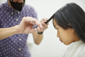 美容院で髪をカットされる子供の様子
