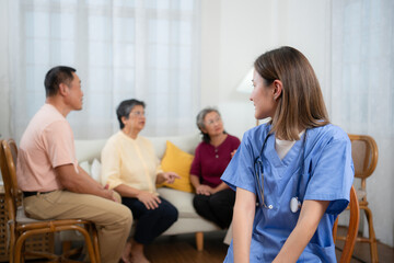 Fototapeta premium Portrait of Asian female nurse using digital tablet in nursing home with senior people on background