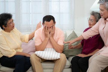 Senior Asian man suffering from serious illness sitting on the sofa With friends coming to visit and give encouragement for the treatment.