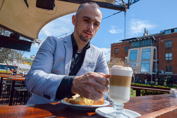 adult business man drinking cup of coffee sitting having breakfast outside restaurant