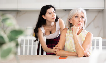 Young woman apologizes to older woman after argument in kitchen at home