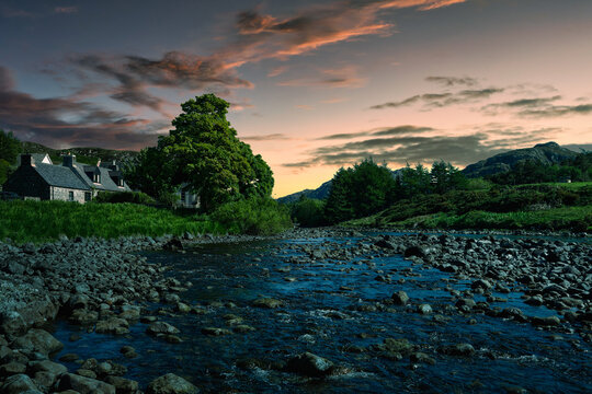 2023-06-09 A ROCKY RIVER IN POOLEWE SCOTLAND WITH A BEAUTIFUL SKY AND GREEN FOLIAGE