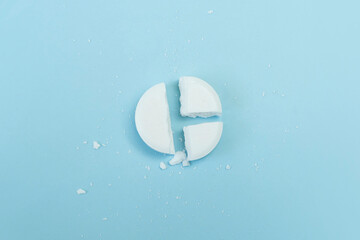 Painkillers and healthcare concept. round tablet was divided equally. Top view of white whole and broken round pills lying on blue background with copy space