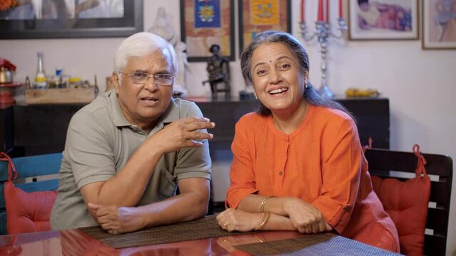 An elderly couple is talking on a video call - use of technology  adoption of technology by elderly . A happily retired Indian couple is making a video call together - modern technology  calling fa...